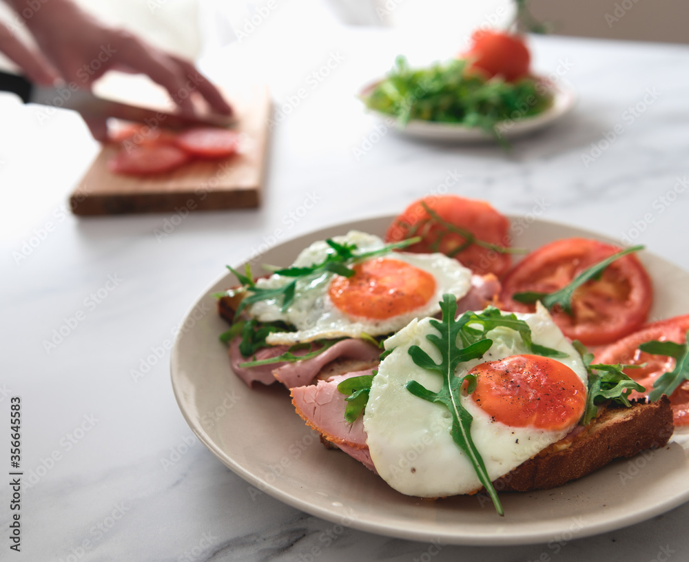 ham and egg on toast with sliced tomatoes and rocket leafs.