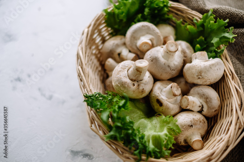 Champignon mushrooms in a basket with herbs on the table. Top view