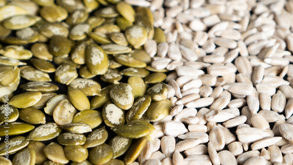 Obraz premium Top view of different seeds as a background. Two parts of sunflower and pumpkin seeds. Healthy food. Seeds texture