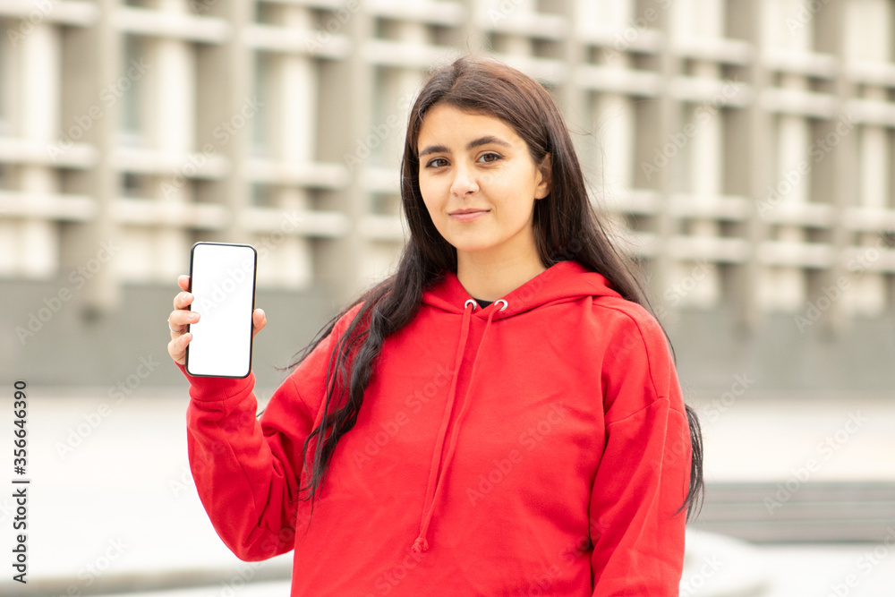 Dark-skinned woman shows a blank phone screen on the street Dark-skinned woman shows a blank phone screen on the street