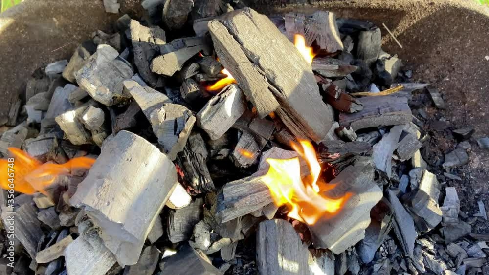 wooden coals burning with hot flames in a bbq grill in a top down shot wooden coals burning with hot flames in a bbq grill in a top down shot