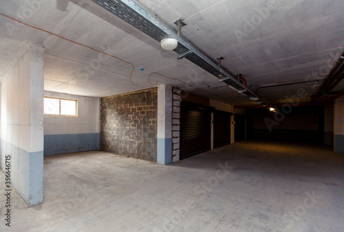 Parking spaces in the basement of an apartment building are separated by walls. some Parking spaces have roller shutters
