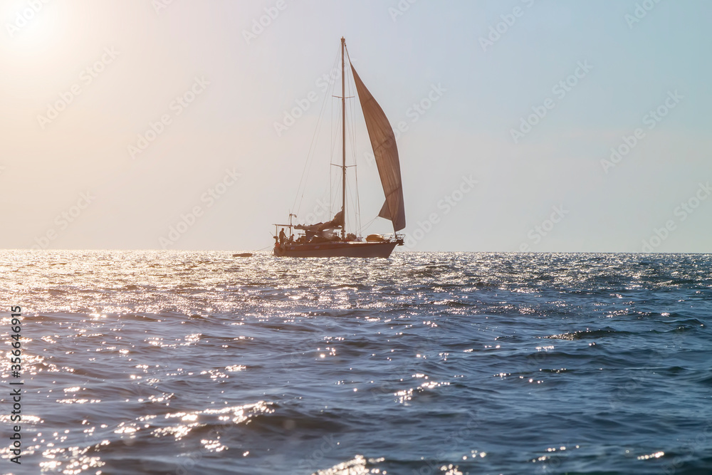 photo of silhouette of sailing yacht in the open sea in the contra light