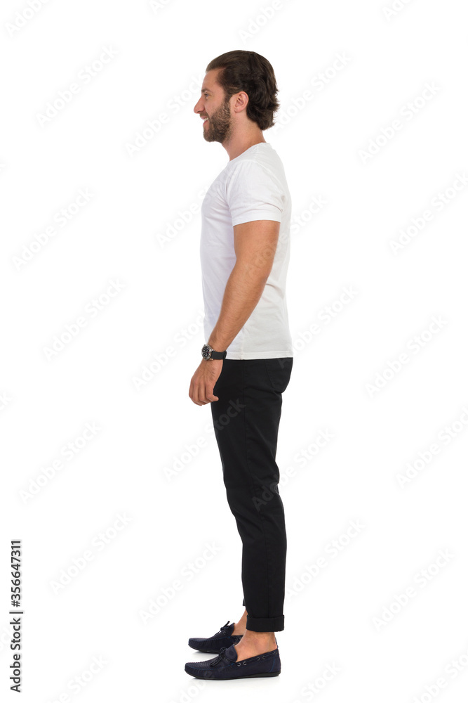 Man In Mocassins, Black Trousers And White T-Shirt Is Standing Relaxed. Side View. Man In Mocassins, Black Trousers And White T-Shirt Is Standing Relaxed. Side View.