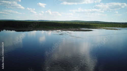 Aerial view of river Kama  Perm krai  Russia. Rural landscape from above  water waves  cloud reflection in water  trees on the coast  summer sun day. Copy space.