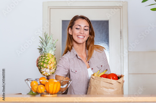 Portrait of beautiful young woman grocery shopping bag with vegetables at home. Young woman holding grocery shopping bag with vegetables Standing in the kitchen.