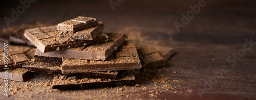 Bars of dark chocolate and cocoa on brown wooden background. Close up view
