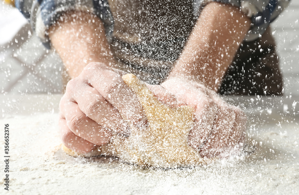Young man kneading dough at table in kitchen, closeup Young man kneading dough at table in kitchen, closeup