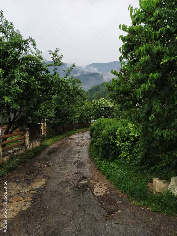 View on a broken village road after rain. Evaporations at the mountains. Traveling and hiking.