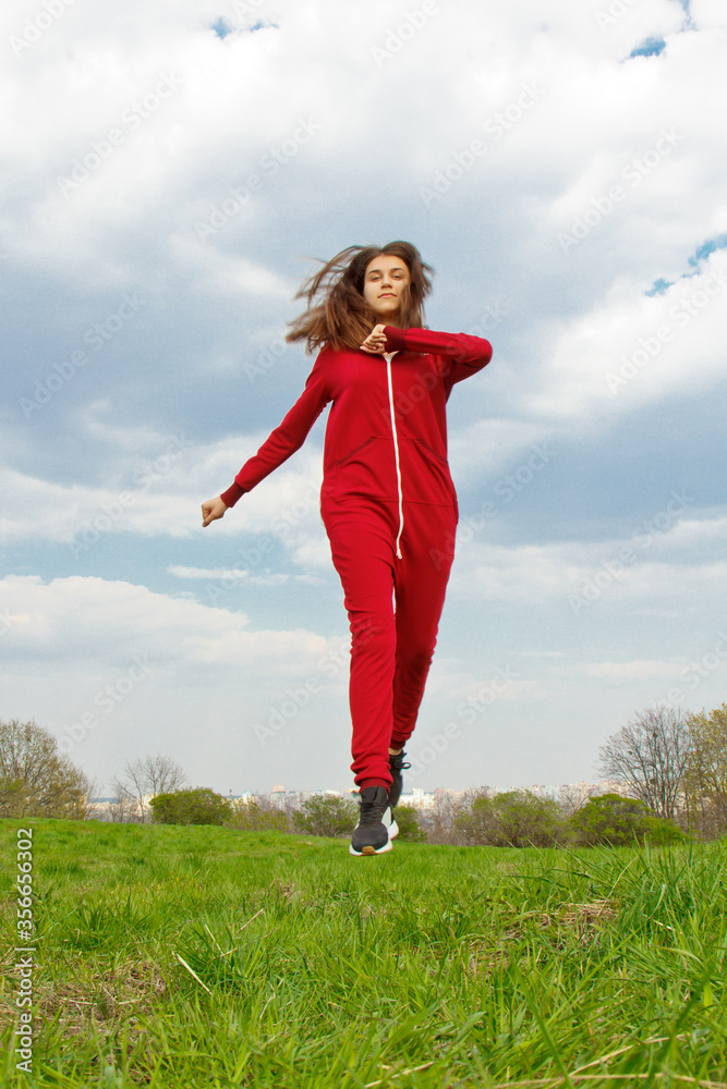 Beautiful, young girl in a tracksuit plays sports in the park on the nature. Healthy lifestyle.