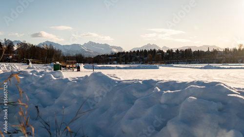 Winter landscape of frozen Westchester Lagoon and the mountains of Chugach Park in the back. Taken from Margaret Eagan Sullivan Playground. Near downtown Anchorage, Alaska. Snow. Taken at sunrise.