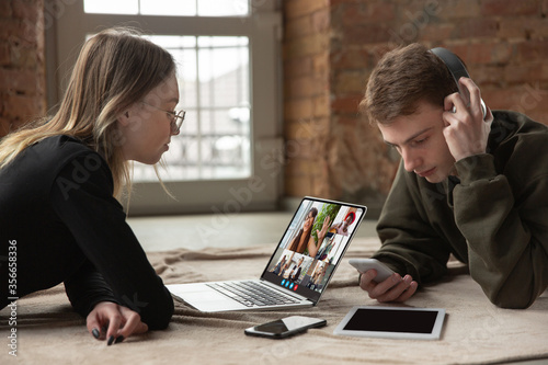 Young man and woman participate video conference looking at laptop screen during virtual meeting, videocall webcam app for business, close up. Remote working, freelance, education, lifestyle concept.