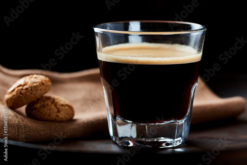 Coffee in glass cup with amaretti (Italian biscuits) on dark background. Close up. 
