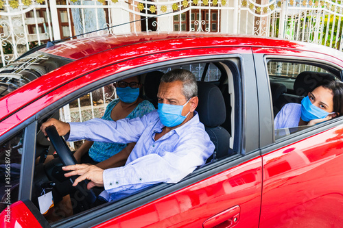 Mature couple with their daughter driving around in the car in a medical mask. Concept of pandemic © Hector Pertuz