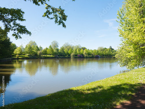 Beautiful lake during the spring season, Flers, Normandy, France. Green foliage in the background that reflects in the water. Sunny day in the park. photo