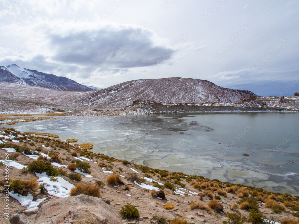 Snowy andes mounatins and frozen lake near Salar De Uyuni, Bolivia