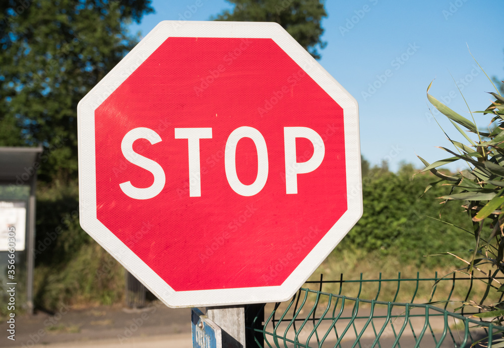 Stop traffic sign close up at a road intersection. English language. Beautiful colorful surroundings.