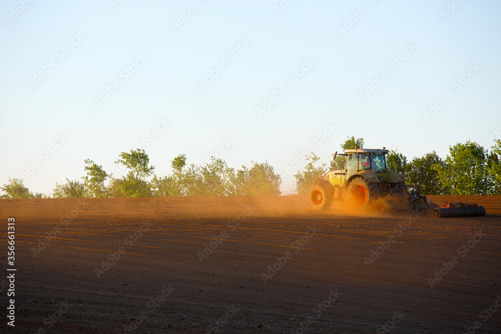 Fototapeta premium Tracteur en campagne labourant le champ en été.