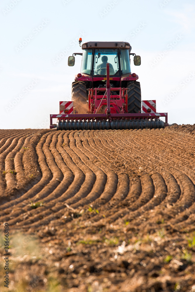 Obraz premium Tracteur labourant un champ pour semer du maïs.