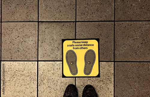 Newyork , usa - 8 June ,2020 : Closeup of feet standing onthe floor with yellow social distance sign - image  