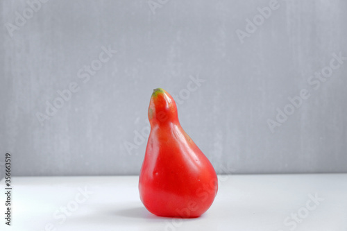 Pear-shaped red tomato on a grey background photo