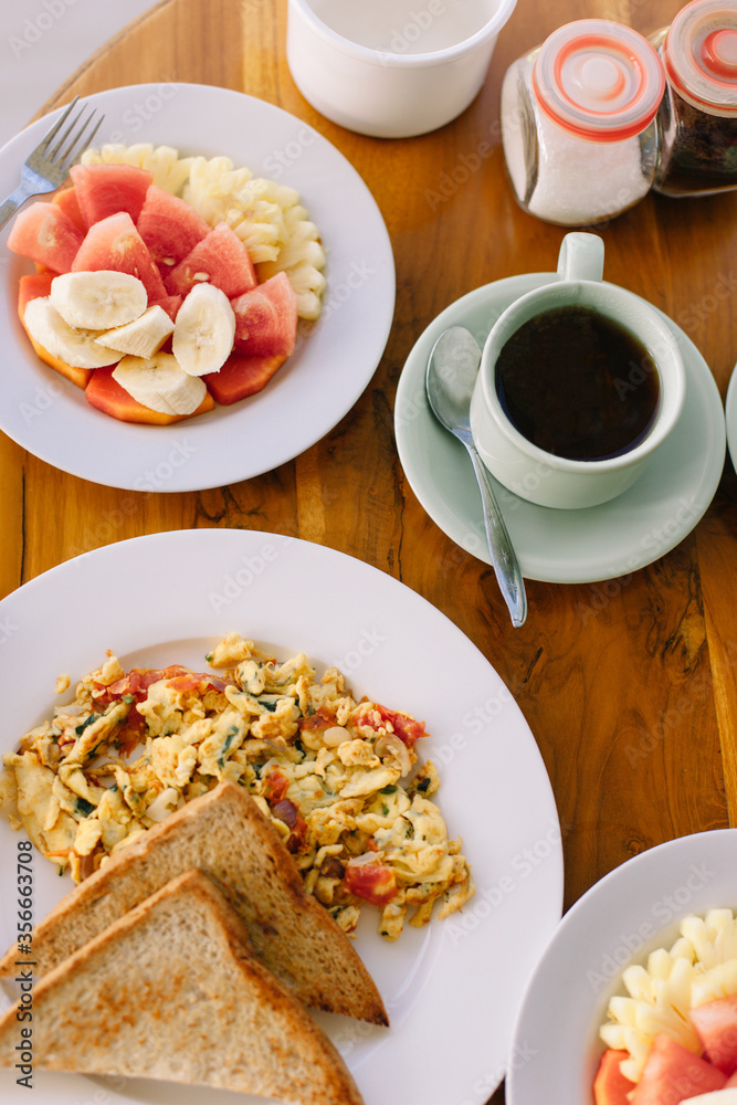 Fresh delicious breakfast of omelet with toast and fruit plate. Near a cup of tea.
