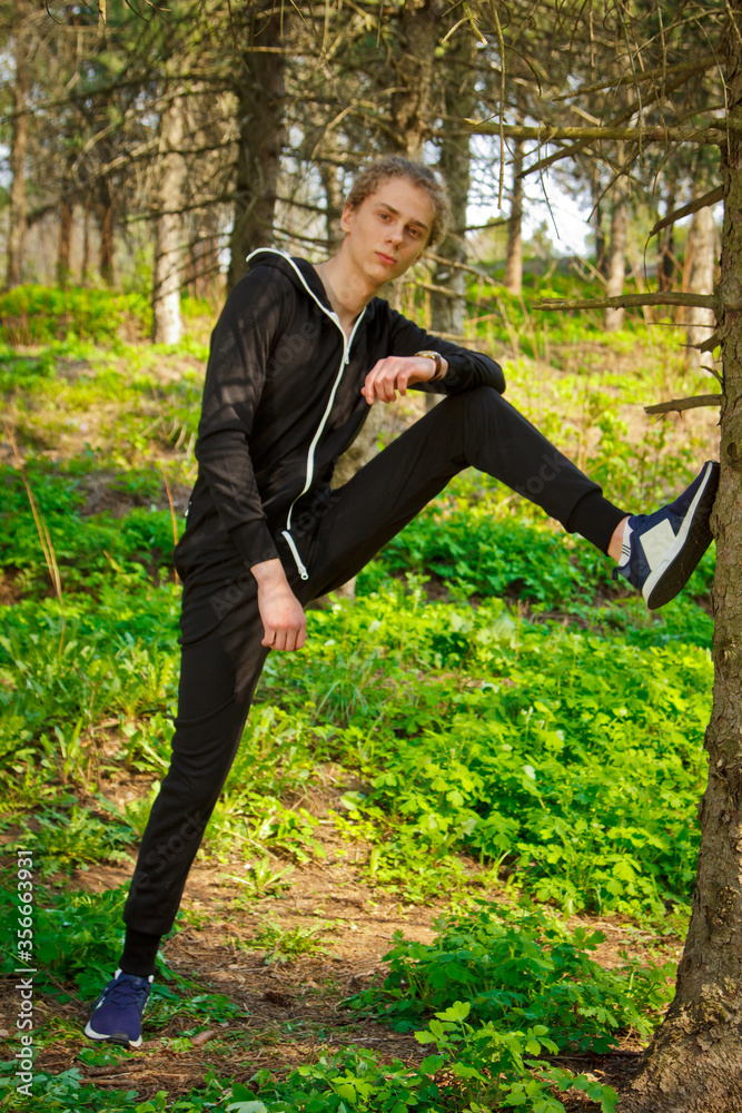 Handsome, young guy in a tracksuit plays sports in the park on the nature. Healthy lifestyle. Handsome, young guy in a tracksuit plays sports in the park on the nature. Healthy lifestyle.