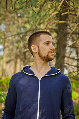 Handsome, young guy in a tracksuit plays sports in the park on the nature. Healthy lifestyle.