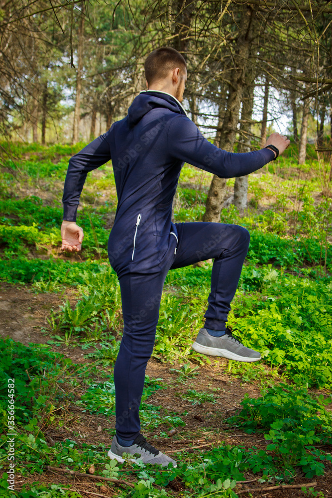 Handsome, young guy in a tracksuit plays sports in the park on the nature. Healthy lifestyle. Handsome, young guy in a tracksuit plays sports in the park on the nature. Healthy lifestyle.