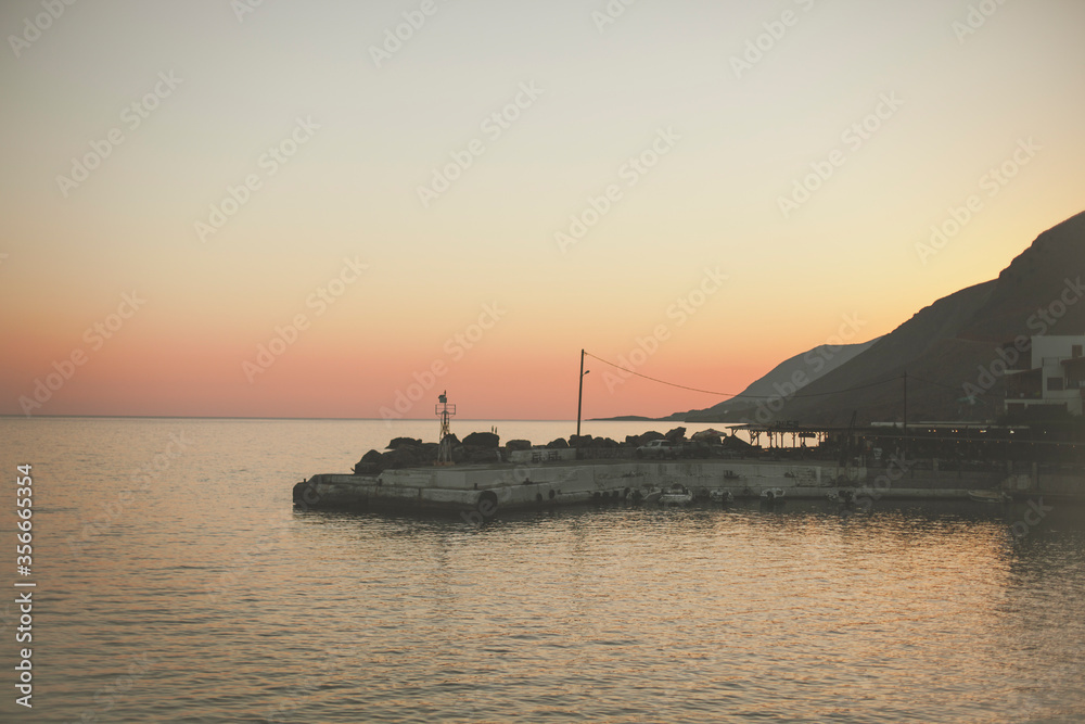 Sunset on the background of mountains and a small port on the Mediterranean Sea
