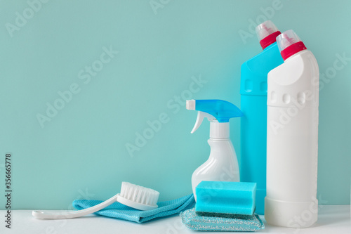White bottles of household chemicals on a blue background with copy space. Cleaning in the apartment, house. Inventory for the maid.