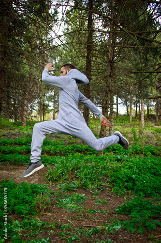 Handsome, young guy in a tracksuit plays sports in the park on the nature. Healthy lifestyle. © Yuliia