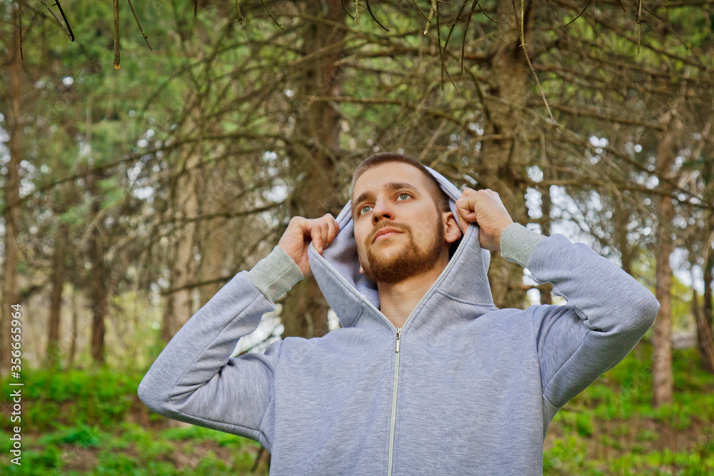 Handsome, young guy in a tracksuit plays sports in the park on the nature. Healthy lifestyle.