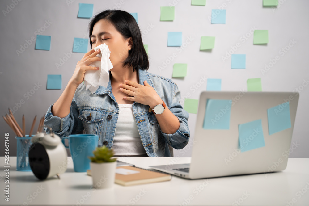 Asian woman working on a laptop was sick with fever sitting at home office. WFH. Work from home. Prevention Coronavirus COVID-19 concept. Asian woman working on a laptop was sick with fever sitting at home office. WFH. Work from home. Prevention Coronavirus COVID-19 concept.