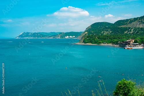 Beautiful coast of the Black Sea on a background of green hills. Coastline of the blue sea with green mountains.