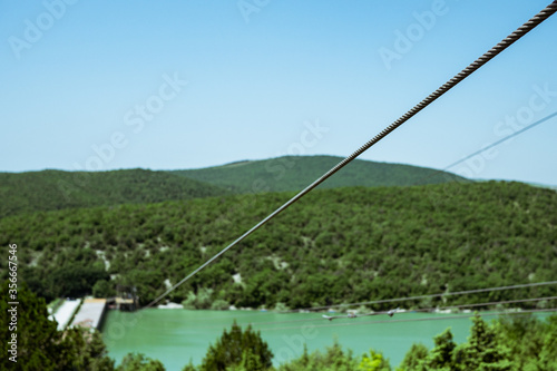 Metal cable for descent into the valley. Iron cable close-up against the backdrop of a huge forest.