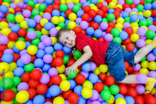 the boy lies in the pool with colored balls