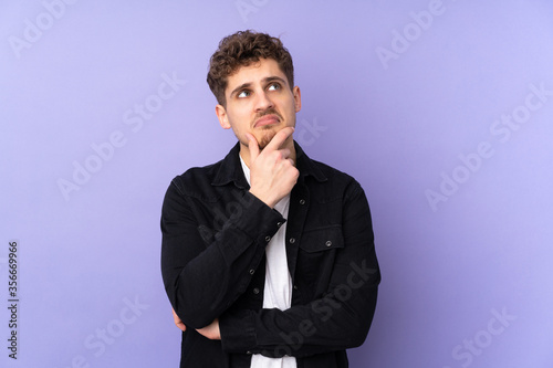 Caucasian man isolated on purple background having doubts © luismolinero
