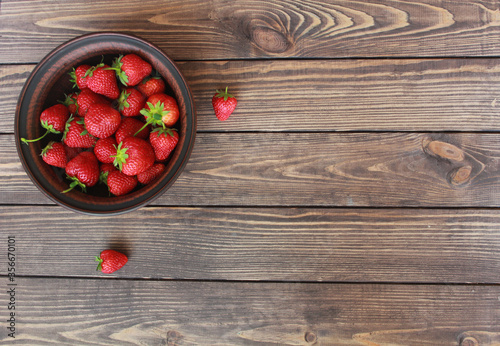 Top view of fresh strawberries in a ceramic bowl  on a wooden table