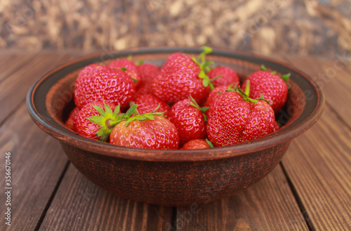  fresh strawberries in a ceramic bowl  on a wooden table