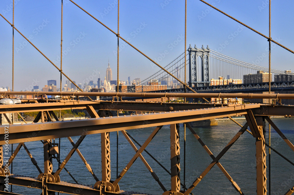 Vue sur le pont de manhattan à travers la structure d'acier du pont de brooklyn et gratte-ciel à l'horizon dans un soleil matinal. Vue sur le pont de manhattan à travers la structure d'acier du pont de brooklyn et gratte-ciel à l'horizon dans un soleil matinal.
