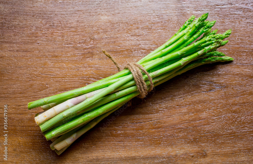 Asparagus. Fresh green asparagus tied with a rope on a wooden background. Asparagus. Fresh green asparagus tied with a rope on a wooden background.