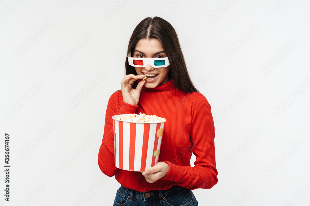 Photo of brunette woman wearing 3D glasses holding popcorn bucket