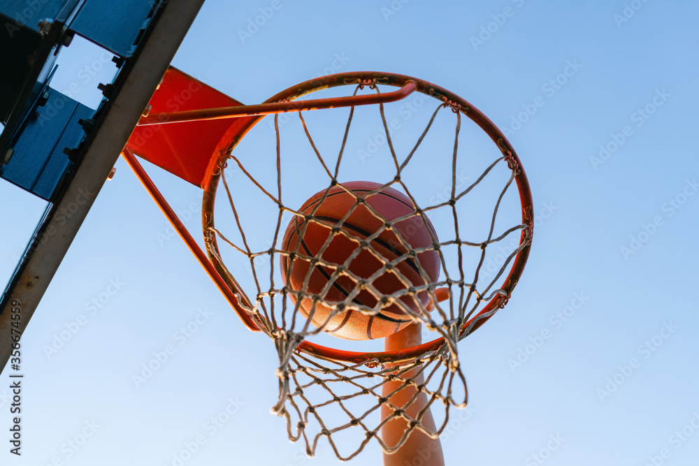 Street basketball slam dunk competition. Close up of ball falling into the hoop. Urban youth game. Concept of success, scoring points and winning