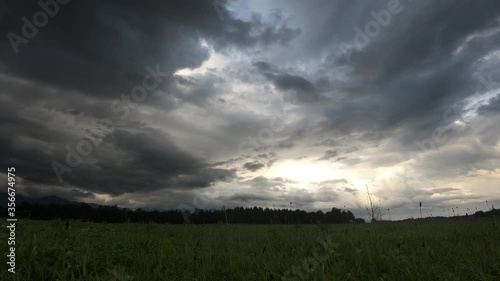Stormy clouds over farming grassland field. Time lapse of dark clouds. Low angle, wide and static shot