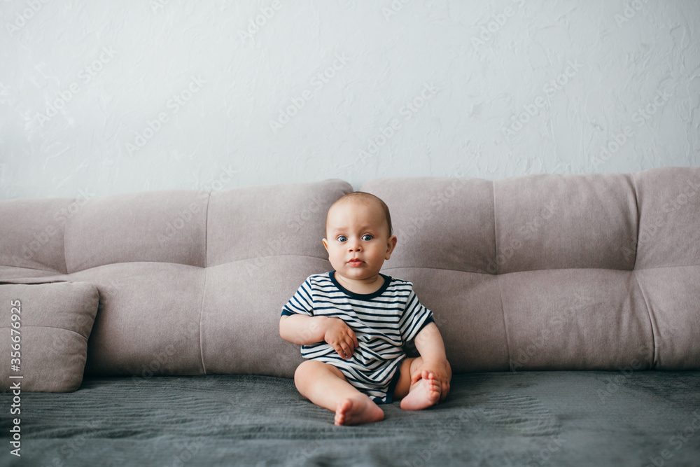 Handsome boy sitting on a gray sofa in a striped T-shirt Handsome boy sitting on a gray sofa in a striped T-shirt