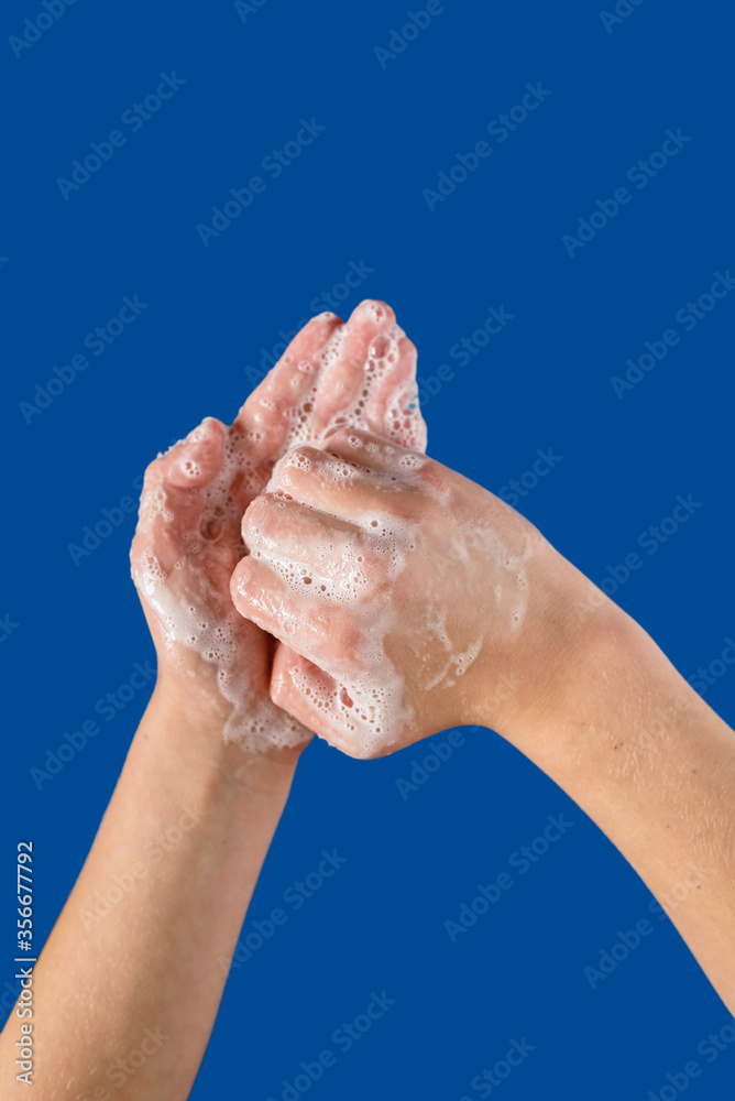 Fototapeta premium Closeup of person cleaning hands with soap, on blue background