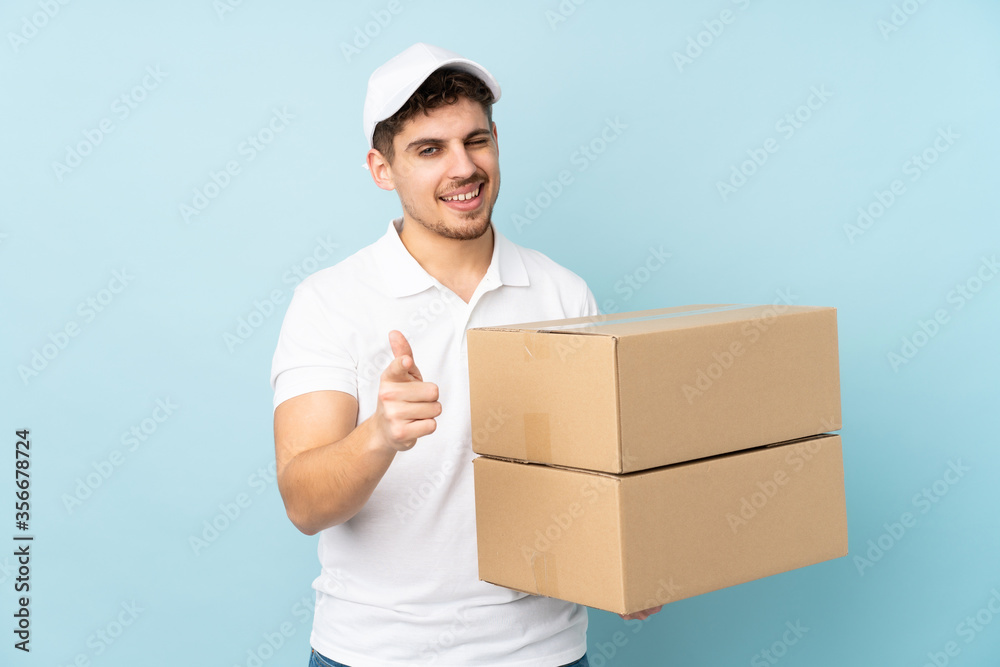 Delivery caucasian man isolated on blue background points finger at you Delivery caucasian man isolated on blue background points finger at you