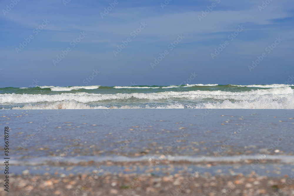 Fototapeta premium Wet sand, a sea with dark-colored waves and a deep blue sky