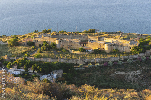 Panoramic view on European medieval fortress on top of hill above Mediterranean sea. Historical heritage, ancient ruins, architecture. Travel destination.